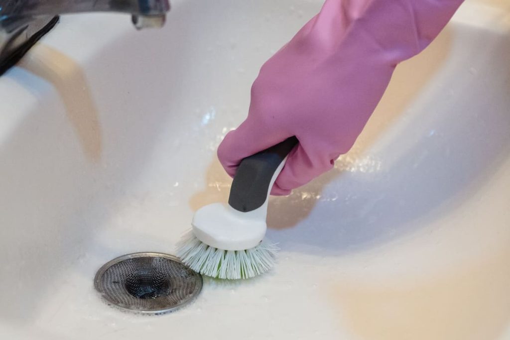 Cleaning a bathroom sink drain with a brush