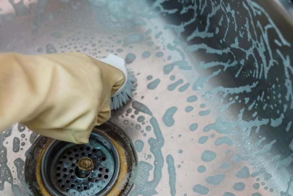 Scrubbing a soapy kitchen sink drain