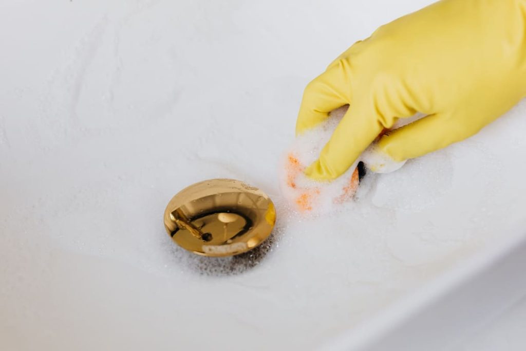 Hand cleaning around a brass sink drain