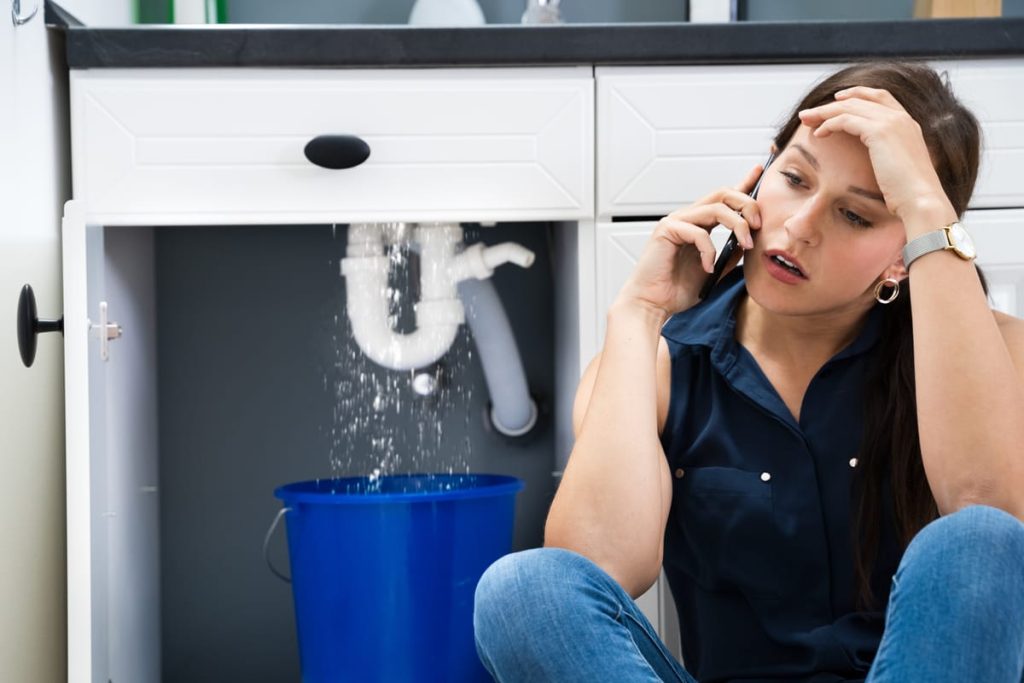Homeowner calling a plumber about a leak under the sink