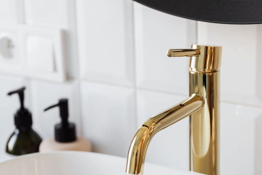 Gold faucet pouring water into a modern sink