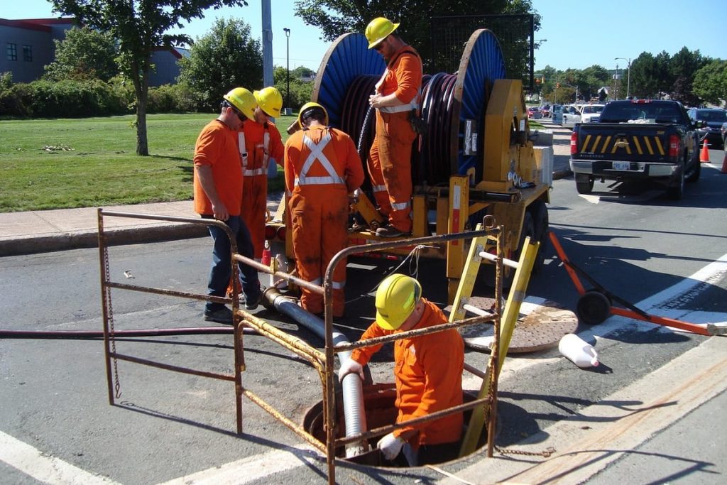 Sewer crew working at an open manhole with a jetting unit