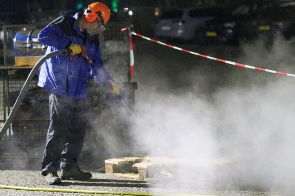 Worker in protective gear using a high-pressure water jet
