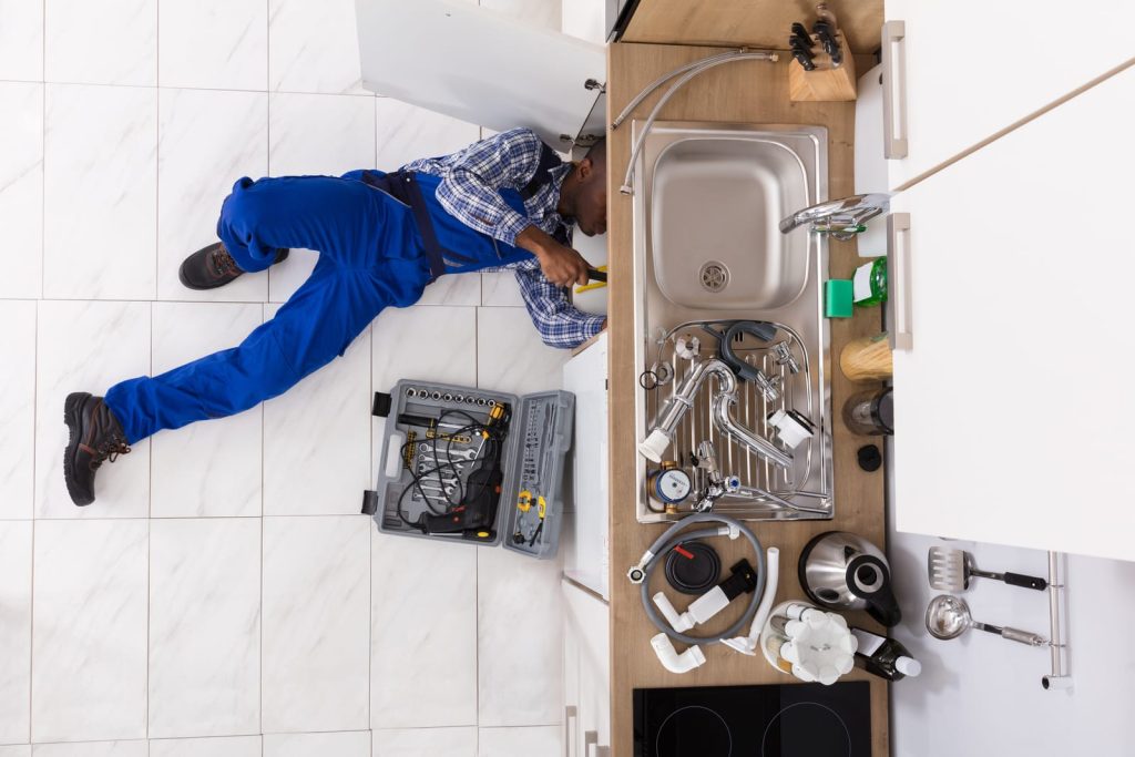 Overhead view of a plumber working under a kitchen sink