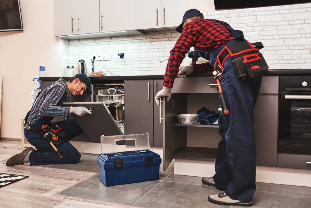 Two plumbers working in a home kitchen