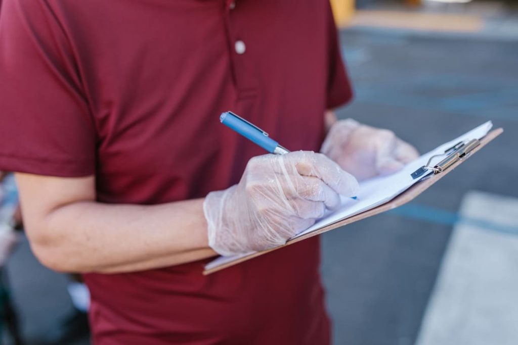 Gloved hand completing a checklist on a clipboard