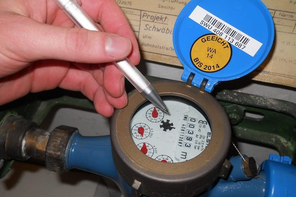 Plumber pointing at the dial of a water meter during a check