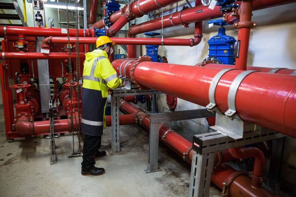 Engineer in safety gear inspecting large pipework and valves