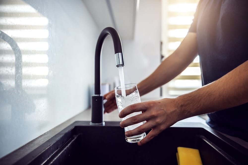Filling a glass of water at a kitchen faucet