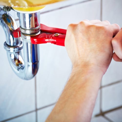 Wrench tightening a chrome sink trap