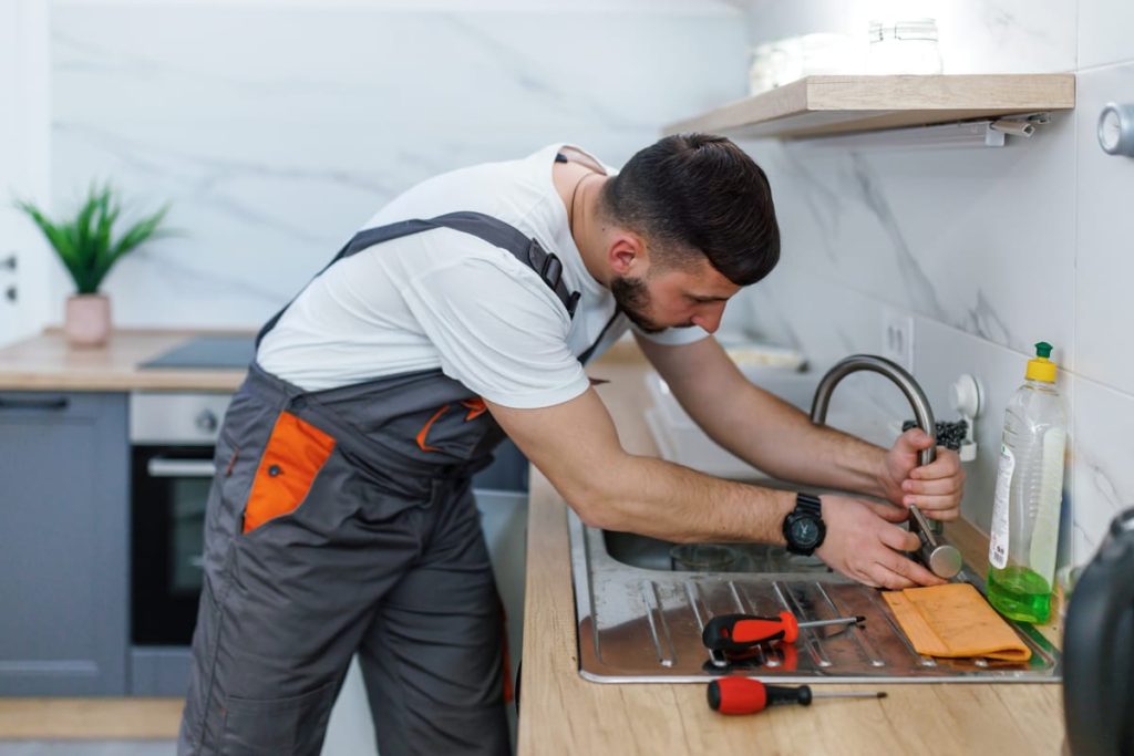 Plumber repairing a kitchen faucet