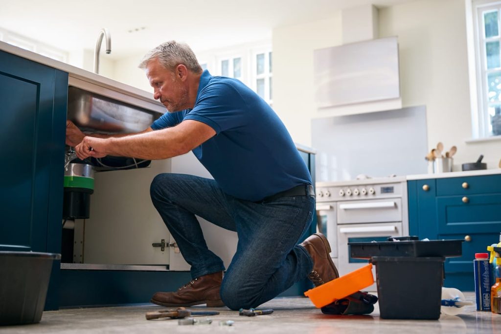 Plumber working under a kitchen sink