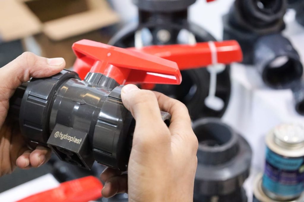 Hands fitting a ball valve onto a pipe