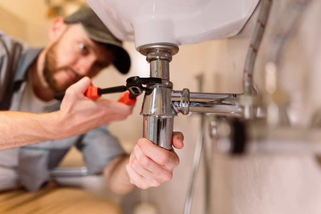 Plumber tightening a sink drain with a wrench