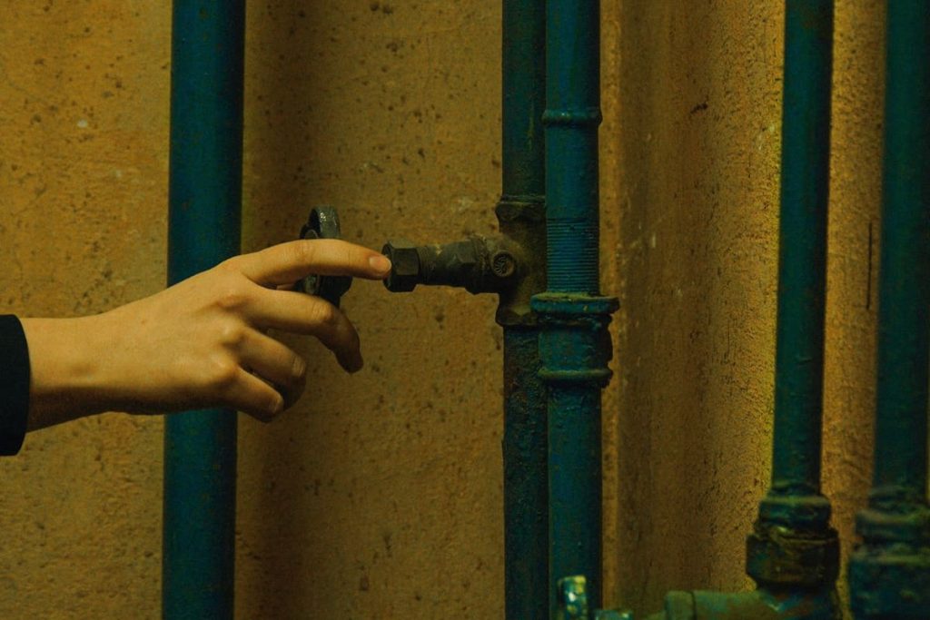 Hand adjusting metal pipes against a concrete wall