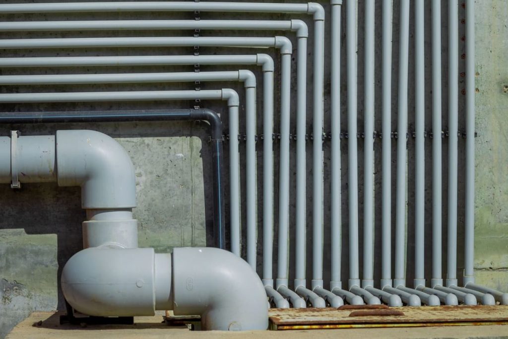 Rows of pipes against a concrete wall
