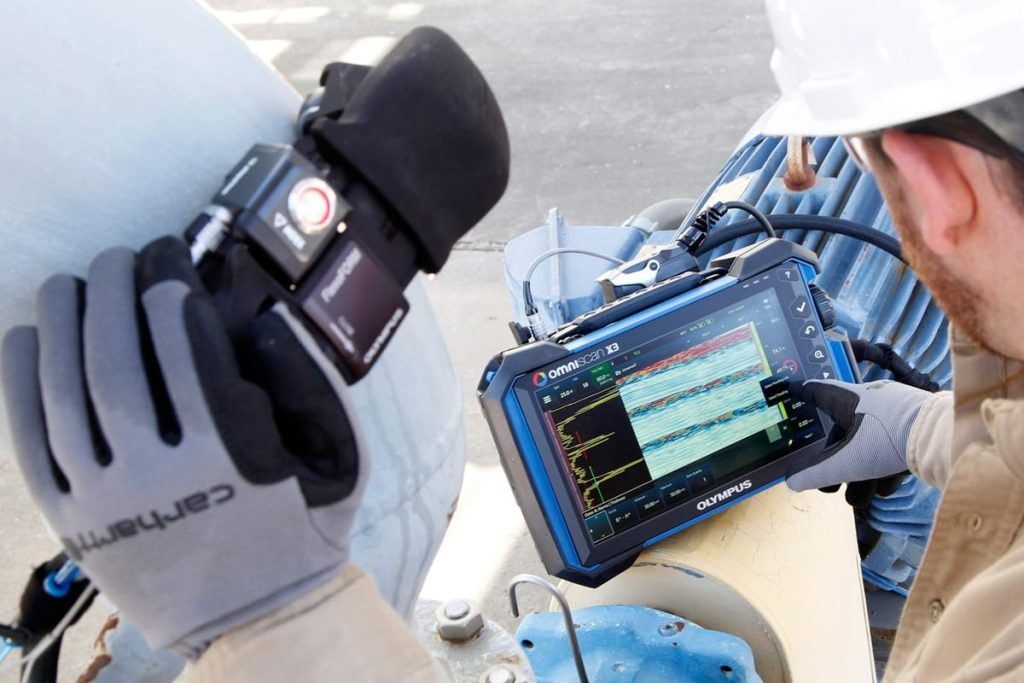 Technician checking readings on a handheld inspection monitor