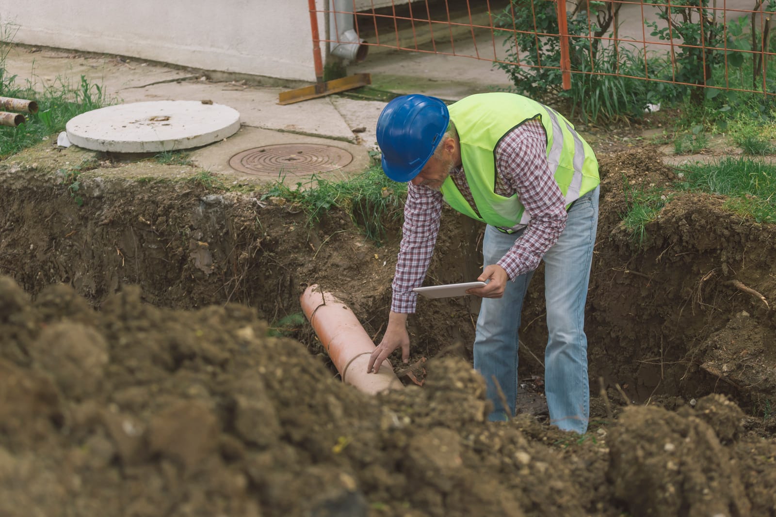 Worker in a trench replacing a sewer pipe