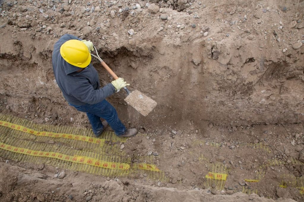 Worker digging a trench with a shovel