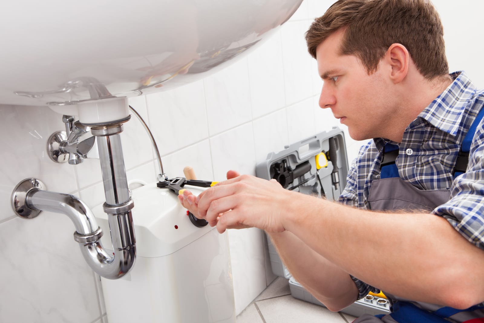 Plumber working on the drain under a sink