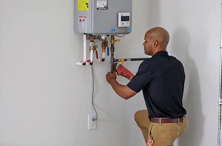 Plumber connecting pipes to a wall-mounted tankless water heater