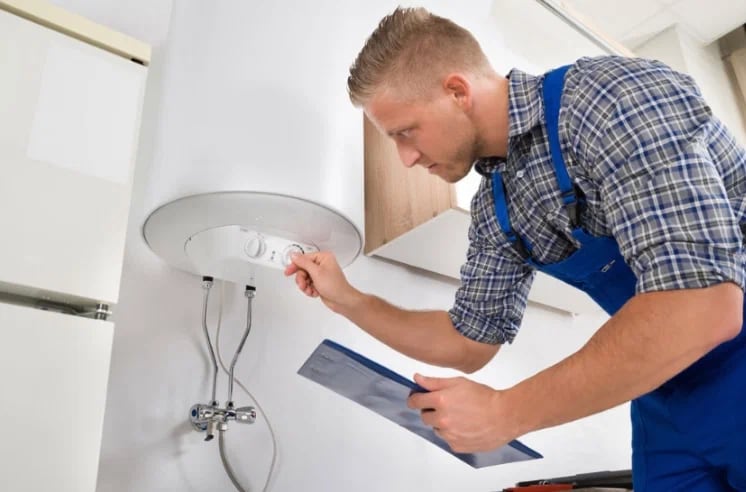 Plumber with a clipboard checking a water heater