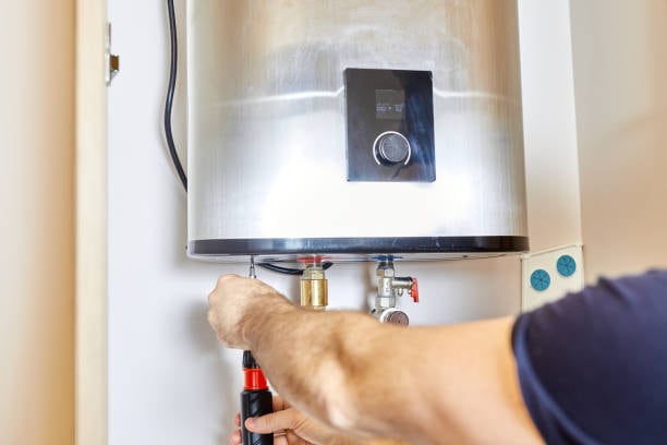 Hands tightening the pipe fittings under a water heater